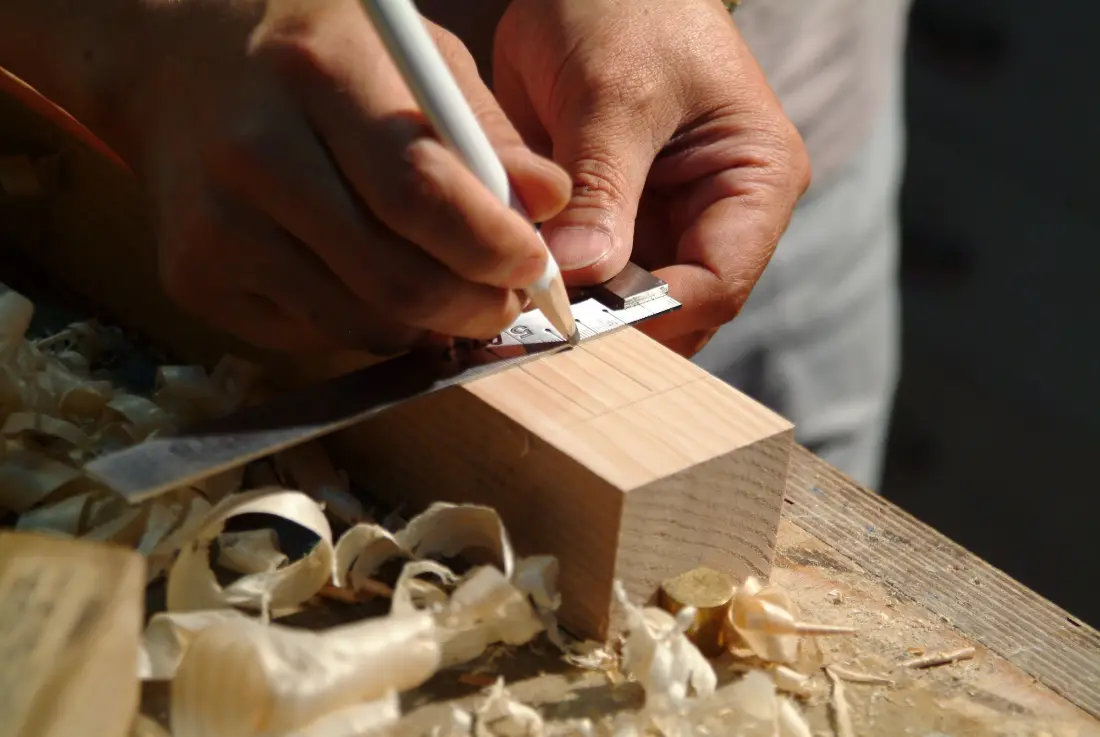 Pencil and steel square marking a cut line on a length of timber