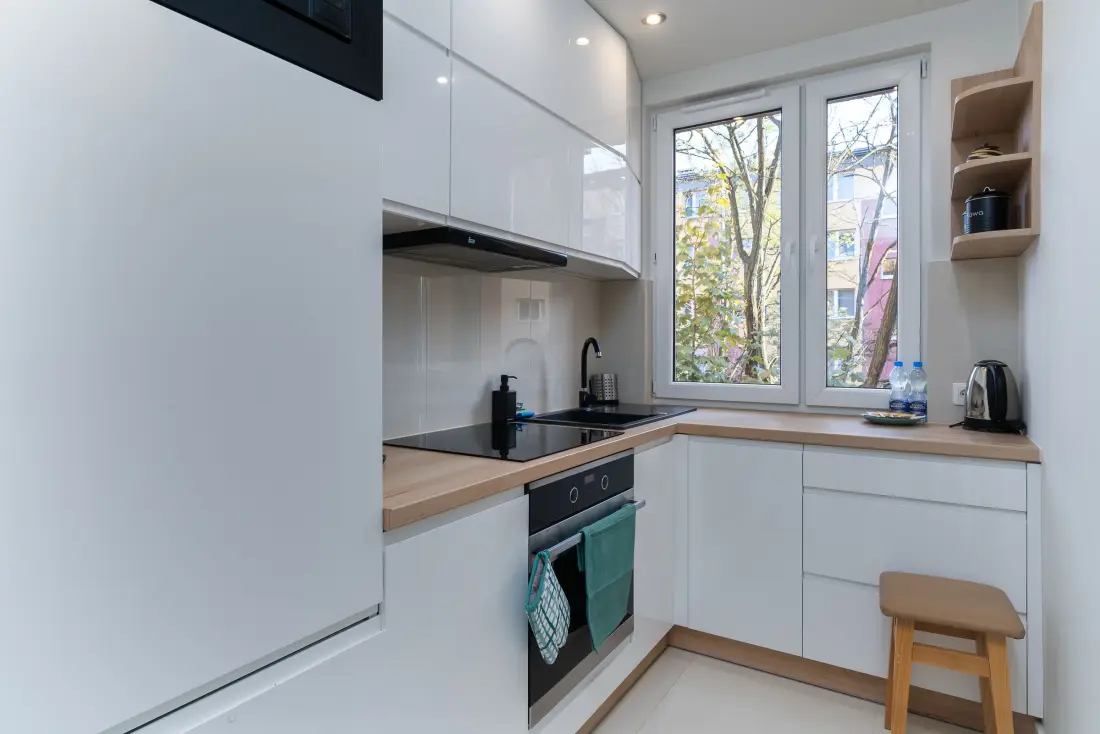 White kitchen with a light timber benchtop, open shelf and window light